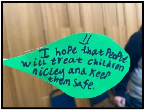 A green leaf with the following written on it: "I hope that people will treat children nicely and keep them safe."