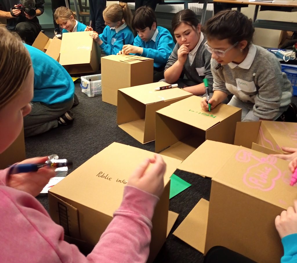 Members of Childrens Parliament work on the floor to engage in a creative process while Exploring Childrens Rights and A.I (2025)