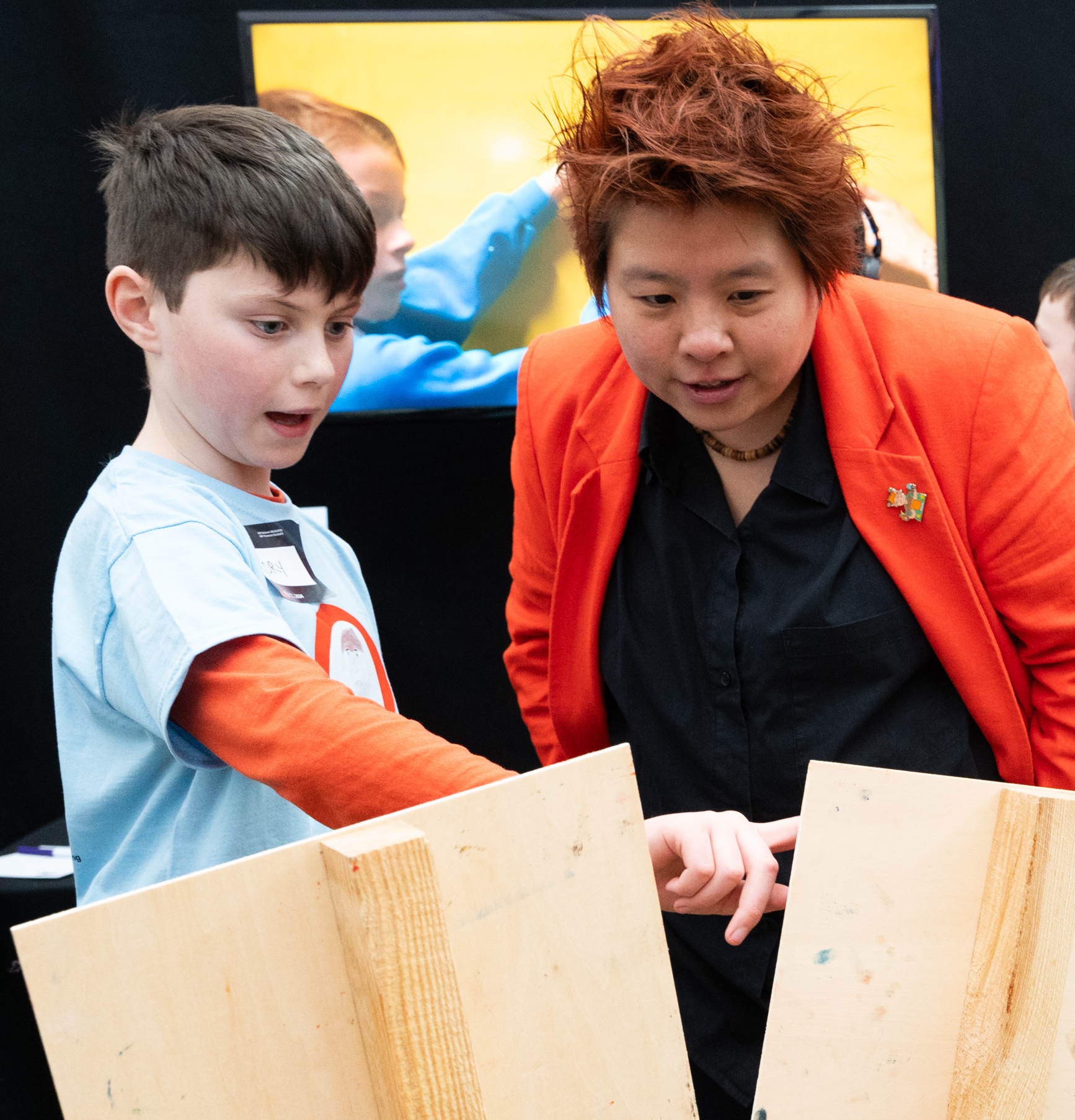 Member of Children's Parliament points at a sign while explaining to an adult