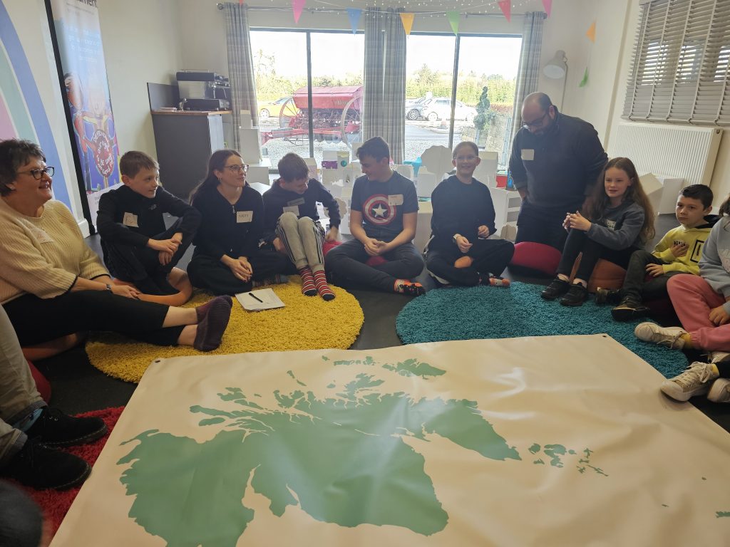 Children's Parliament group sitting around a map of Scotland.
