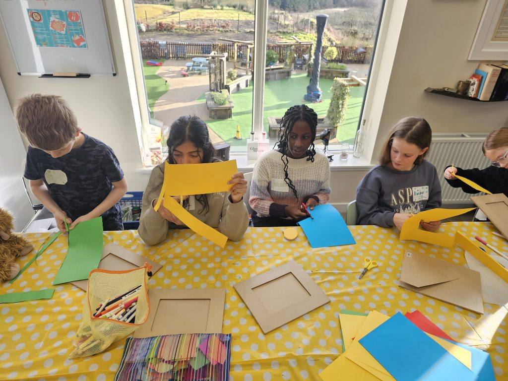 Member's of Children's Parliament chat while they use scissors to cut-out colourful creations.