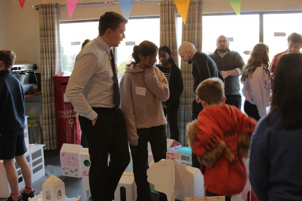 Members of Children's Parliament guide adult visitors through their model town.